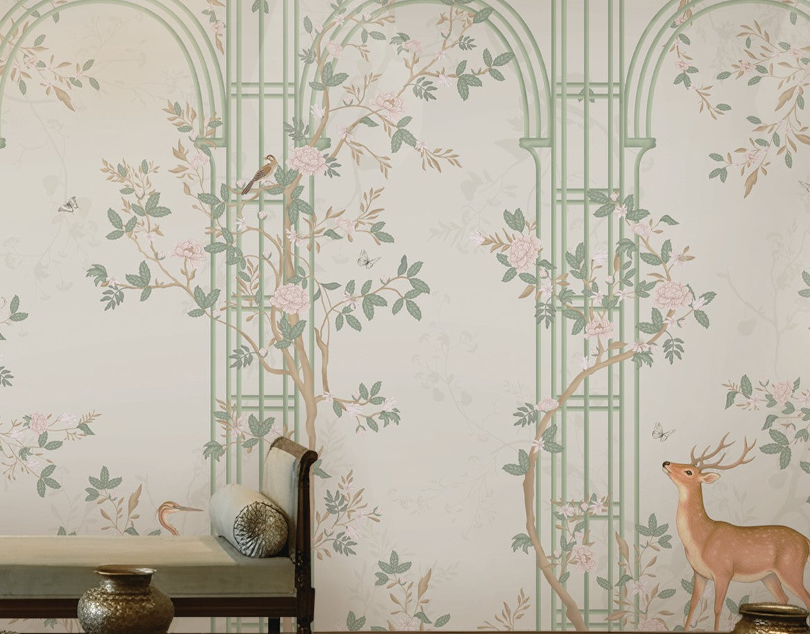 Morning Dew Trellis wallpaper in soft sage green featuring elegant trellis arches, delicate flowering vines, perched birds, graceful butterflies, and botanical details. Displayed in a sophisticated living room with a coffered wood ceiling, ornate chandelier, plush seating, brass accents, and warm wood flooring, the mural creates a serene garden-inspired backdrop that blends timeless elegance with luxurious interior design.