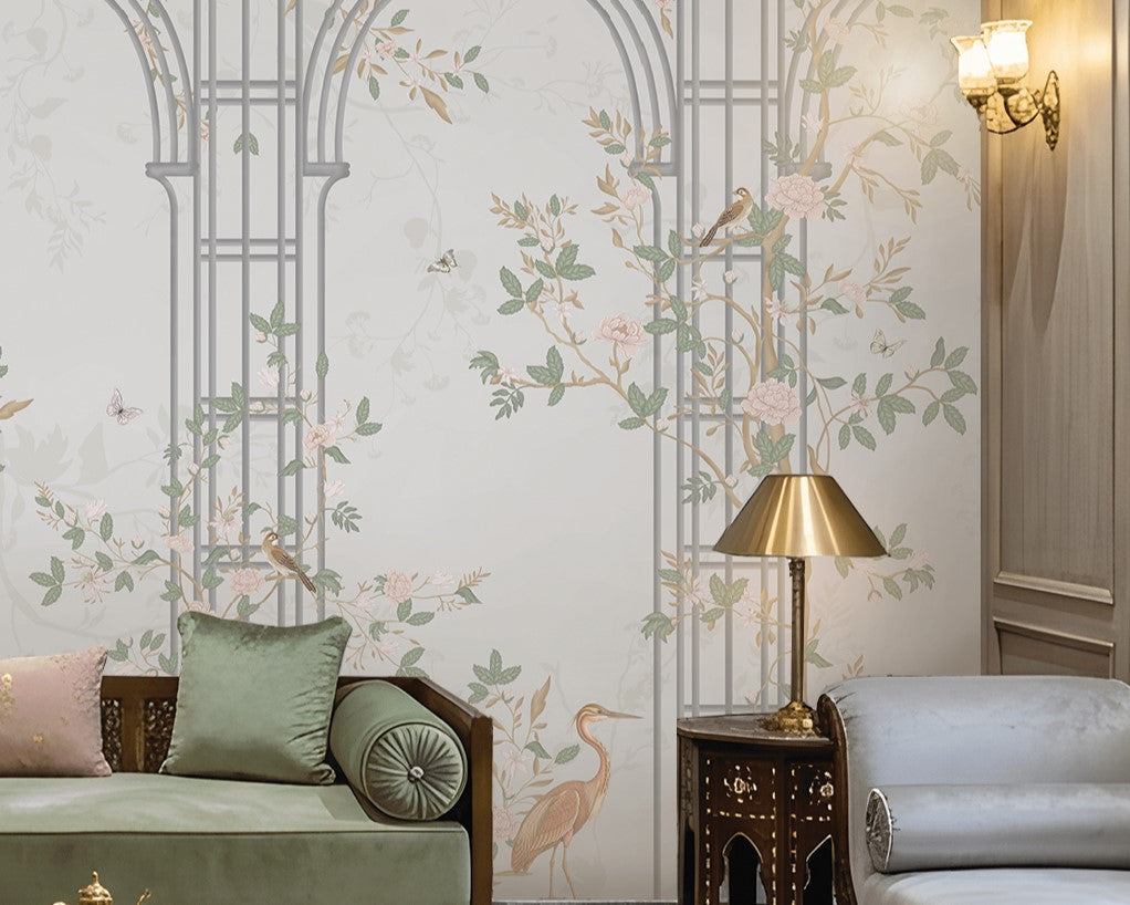 Morning Dew Trellis wallpaper featured in a luxurious living room, showcasing elegant powder blue trellis arches intertwined with delicate floral vines, blooming branches, birds, and botanical motifs. Surrounded by intricately carved wall panels, crystal chandeliers, plush seating, brass accents, and soft lighting, the mural creates a refined blend of classic elegance, garden-inspired beauty, and timeless sophistication.