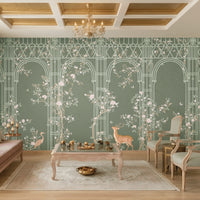 Morning Dew Trellis wallpaper in deep sage green featuring elegant arched trellis detailing, delicate flowering branches, perched birds, butterflies, and graceful woodland animals. Displayed in a luxurious living room with a coffered wood ceiling, crystal chandelier, blush-toned chaise lounge, vintage armchairs, and warm wood flooring, the mural creates a sophisticated garden-inspired focal point that blends classic elegance with nature-inspired charm.