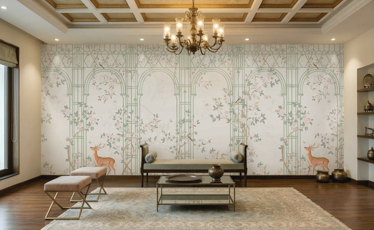 Morning Dew Trellis wallpaper in soft sage green featuring elegant trellis arches, delicate flowering vines, perched birds, graceful butterflies, and botanical details. Displayed in a sophisticated living room with a coffered wood ceiling, ornate chandelier, plush seating, brass accents, and warm wood flooring, the mural creates a serene garden-inspired backdrop that blends timeless elegance with luxurious interior design.