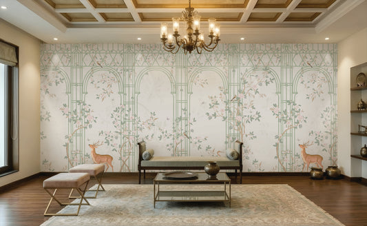 Morning Dew Trellis wallpaper in soft sage green featuring elegant trellis arches, delicate flowering vines, perched birds, graceful butterflies, and botanical details. Displayed in a sophisticated living room with a coffered wood ceiling, ornate chandelier, plush seating, brass accents, and warm wood flooring, the mural creates a serene garden-inspired backdrop that blends timeless elegance with luxurious interior design.