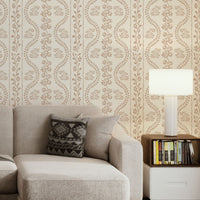 A high-resolution detail of the Floral Seamless Wallpaper in Muted Beige, showcasing the rhythmic vertical vine structure and delicate botanical sprigs. The image highlights the fine, hand-drawn illustrative style and the soothing, neutral tones of the tan and cream palette.