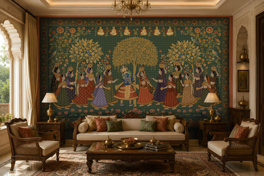 A luxurious living room features a large, wall-to-wall mural inspired by traditional Indian miniature art. At the center, Radha and Krishna stand together beneath a golden tree, surrounded by women in colorful lehengas carrying decorative pots. Intricate floral vines, birds, lotus flowers, and ornate borders frame the scene, with small seated sages depicted along the top. The room is furnished with carved wooden sofas and armchairs, cream upholstery, brass table décor, matching lamps, and a p