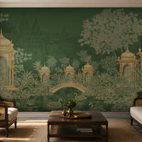 Elegant living room featuring a heritage-inspired mural in deep forest green and antique gold. The mural depicts ornate domed pavilions, lush botanical foliage, a graceful arched bridge, and swans gliding across a tranquil pond, with faint palace architecture in the background. The space is styled with ivory upholstered cane armchairs and sofa, dark wood furniture, green accent cushions, warm brass décor, a wooden coffee table, a natural jute rug, and soft ambient lighting, creating a refined, timeless atmo