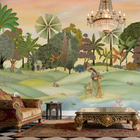 A panoramic Pichwai wallpaper mural featuring a divine Vrindavan Garden scene with hand-painted peacocks, spotted deer, and traditional figures. The design showcases lush tropical trees and a sunset-hued sky, bringing a royal Indian heritage aesthetic to a luxury living room.
