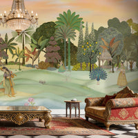 A panoramic Pichwai wallpaper mural featuring a divine Vrindavan Garden scene with hand-painted peacocks, spotted deer, and traditional figures. The design showcases lush tropical trees and a sunset-hued sky, bringing a royal Indian heritage aesthetic to a luxury living room.
