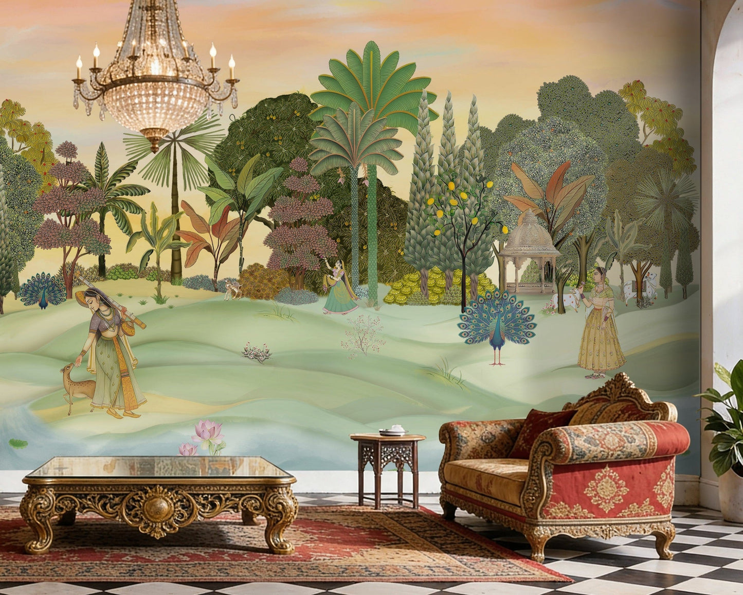 A panoramic Pichwai wallpaper mural featuring a divine Vrindavan Garden scene with hand-painted peacocks, spotted deer, and traditional figures. The design showcases lush tropical trees and a sunset-hued sky, bringing a royal Indian heritage aesthetic to a luxury living room.