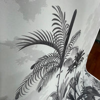 An architectural perspective of a high-ceilinged contemporary lounge featuring the Paradise Palms Mural in Ivory White as a full-scale feature wall. The mural’s expansive botanical vista pairs elegantly with light-toned furniture and organic textures, creating a peaceful and cultured interior sanctuary.