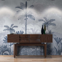 An architectural perspective of a high-ceilinged contemporary lounge featuring the Paradise Palms Mural in Ocean Blue as a full-scale feature wall. The mural’s expansive botanical vista pairs elegantly with crisp white furniture and metallic accents, creating a peaceful and cultured interior sanctuary.