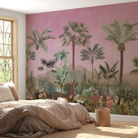 A bohemian-style bedroom featuring a large wall mural of a tropical jungle landscape with green palm trees and botanical plants against a textured pink background, paired with a chunky knit blanket and natural wood window frame.