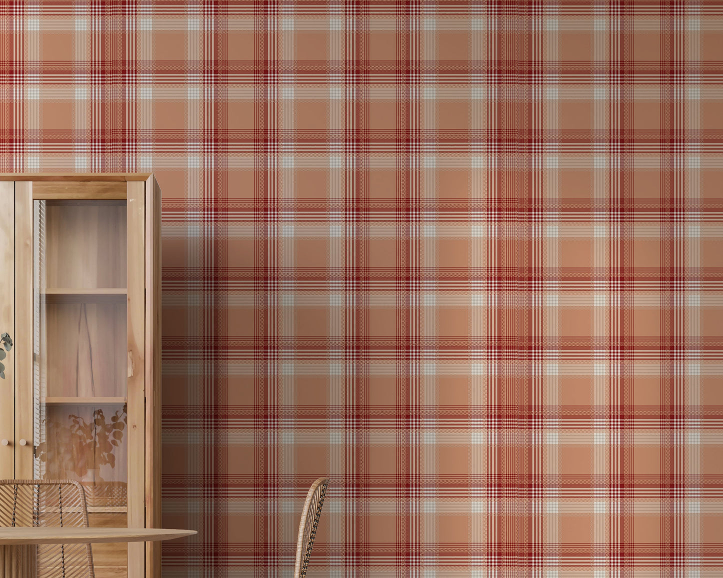 A modern dining area featuring a vibrant cinnamon-blush orange and red plaid wallpaper. On the left stands a tall, light wood display cabinet with glass doors, next to a round wooden dining table with a fluted pedestal base. Woven rattan dining chairs with slim black metal legs are arranged around the table, and a white vase filled with eucalyptus branches rests on top. The room features light-colored vertical wood plank flooring.
