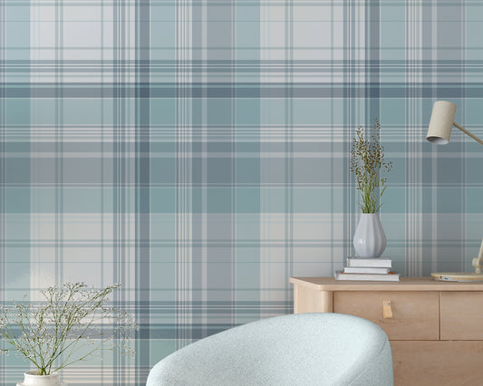 A bright room features a light blue and white plaid wallpaper pattern.
The wallpaper colors include shades of soft aqua, dusty blue, and white lines.
A rounded light blue armchair sits on the dark wood floor.
A small, round wooden side table holds a white vase with flowers.
A large green plant in a white pot stands on the left side.
A light wood dresser with a small desk lamp sits on the right.