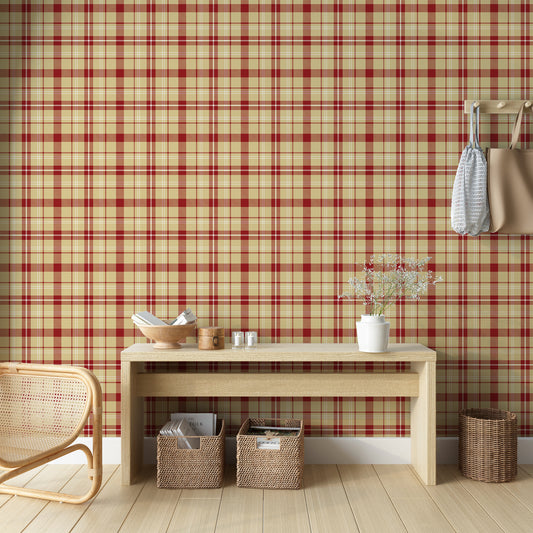 A cozy interior featuring red and beige plaid wallpaper with a woven fabric appearance. The room includes a light wood console table with small decorative items and flowers, woven storage baskets underneath, a wicker chair, and hanging tote bags on the wall.