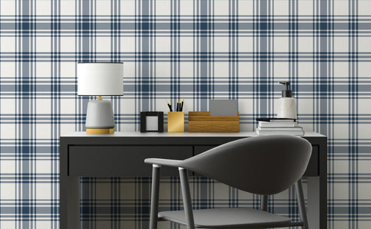 A clean workspace setup features a classic navy blue and white plaid wallpaper.
The detailed design shows intersecting dark blue stripes forming grids on a white base.
In front, a sleek dark grey desk holds a small lamp, notebooks, and office accessories.
A modern dark grey desk chair with a rounded back completes the organized study area.