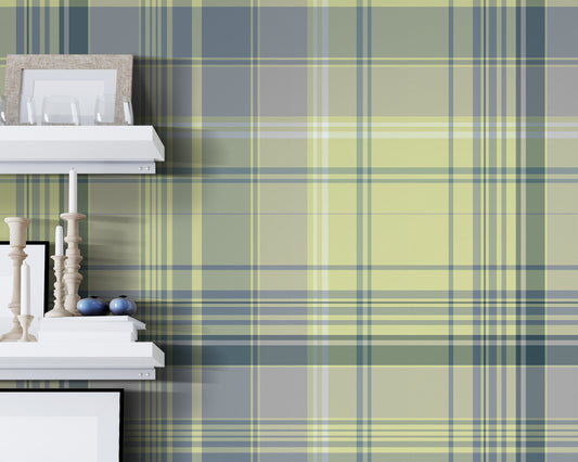 A modern interior featuring green and blue plaid wallpaper with a soft tartan pattern. The room includes floating white shelves with decorative objects, a light wood chair, and a small round table with a black adjustable desk lamp on a light wood floor.