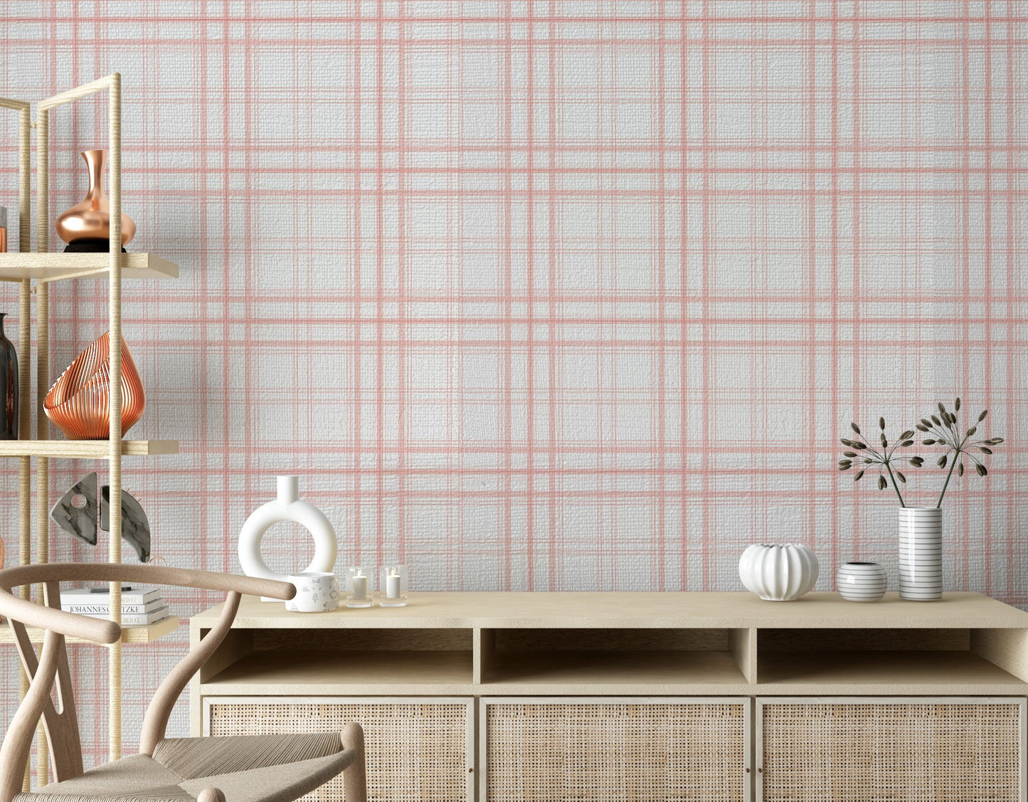 A calm living area features a textured, soft rosy haze pink and white plaid wallpaper.
The detailed design shows thin coral-pink lines intersecting to form clean grids across a light base.
In front, a light wood media console with woven rattan doors is centered nicely.
The relaxing space is accented with a wooden armchair, decorative pottery, and dried botanical stalks.