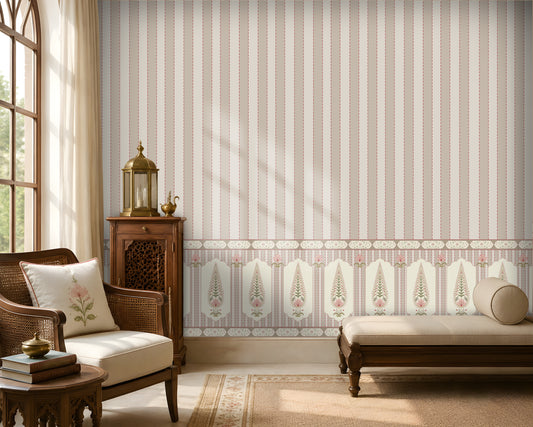 A styled interior room showing wallpaper with vertical pink and cream stripes and a decorative border along the lower portion. A wooden chair with a white embroidered pillow, a small wooden cabinet with a brass lantern, a bench, rug, and window are visible.