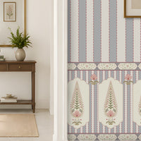 A beautifully styled interior hallway featuring light blue and white vertical striped wallpaper with a decorative border, white walls, a beige woven rug, a potted plant, and an arched doorway in the background.