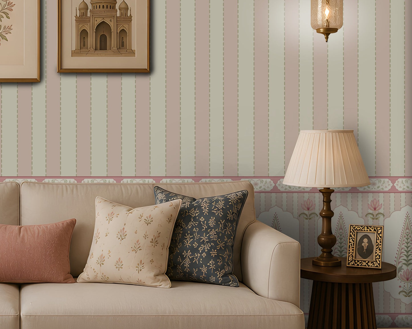 Elegant living room with a cream sofa and patterned blue, cream, and dusty-pink cushions, a carved wooden coffee table, cane armchair, decorative side tables, framed botanical and architectural artwork, brass lanterns, and pastel striped floral wallpaper.
