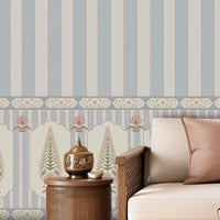 A styled living room featuring a prominent light blue and white vertical striped wallpaper with a decorative border along the bottom. The room is furnished with a cream-colored sectional sofa, wooden coffee table, and neutral-toned decor.