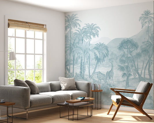 A vintage tropical wallpaper mural in a serene safari landscape is rendered in a monochromatic Cadet Blue color. The hand-drawn design features giraffes and deer amidst lush palm trees and mountains in an etched lithograph style. This nature-inspired, botanical accent wall creates a tranquil and sophisticated atmosphere in modern living spaces, pairing beautifully with grey textiles and natural wood furniture for a contemporary, bohemian-inspired look.