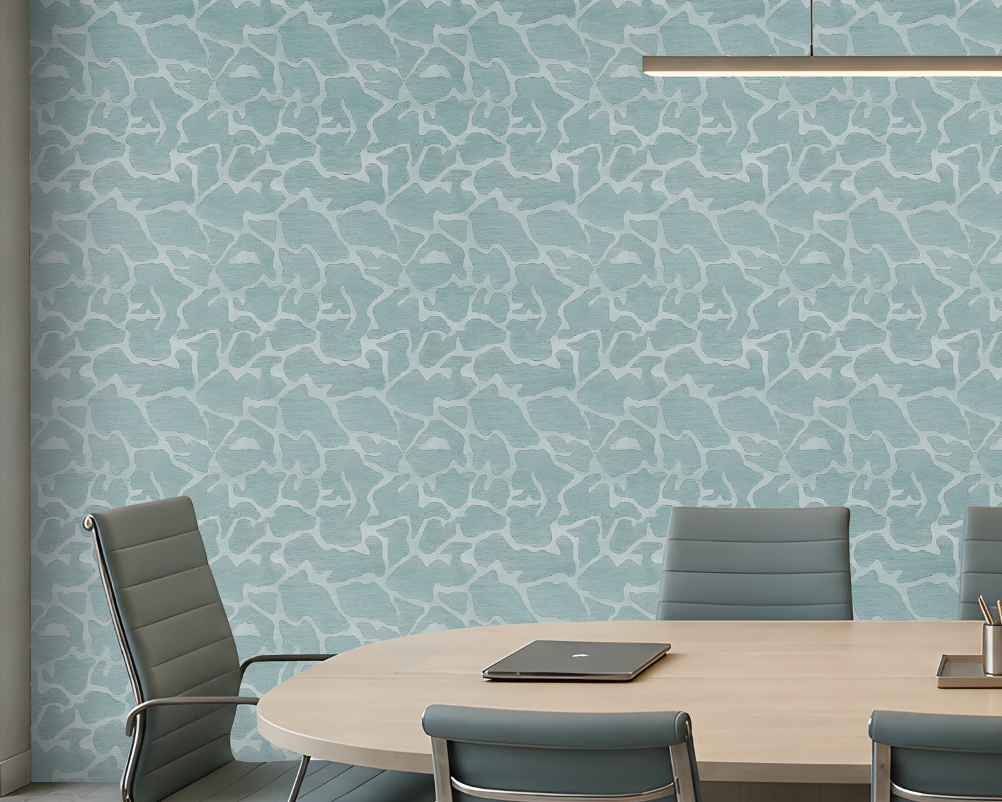 A modern conference room with a large oval wooden table, eight gray office chairs, a light blue patterned accent wall, and built-in shelving on the right side.