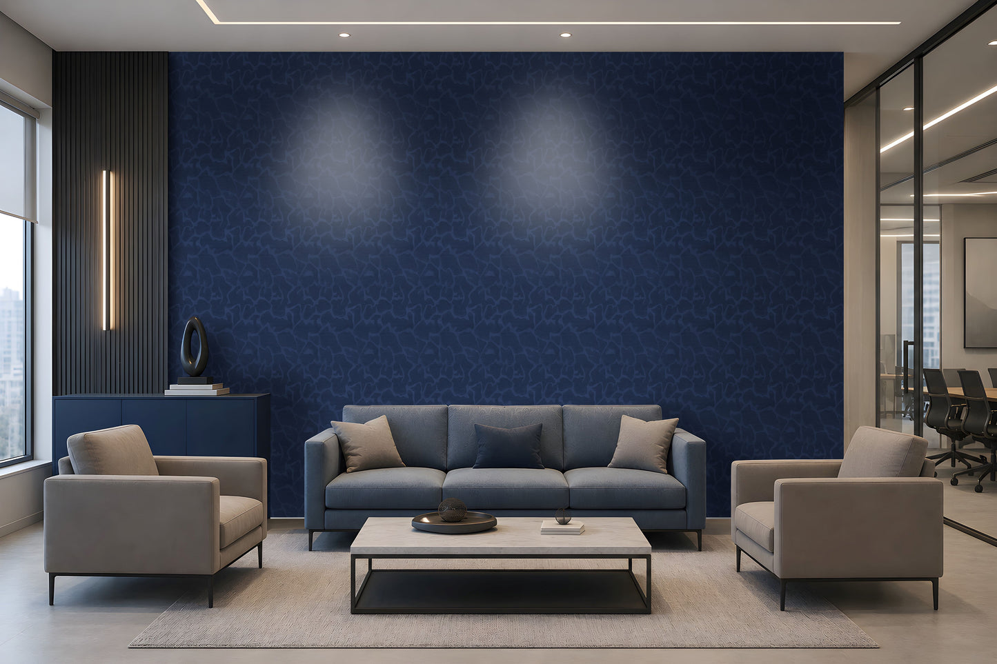 A modern living room setup featuring a prominent dark blue textured wallpaper accent wall behind a gray three-seater sofa, flanked by two light gray armchairs and a white coffee table.