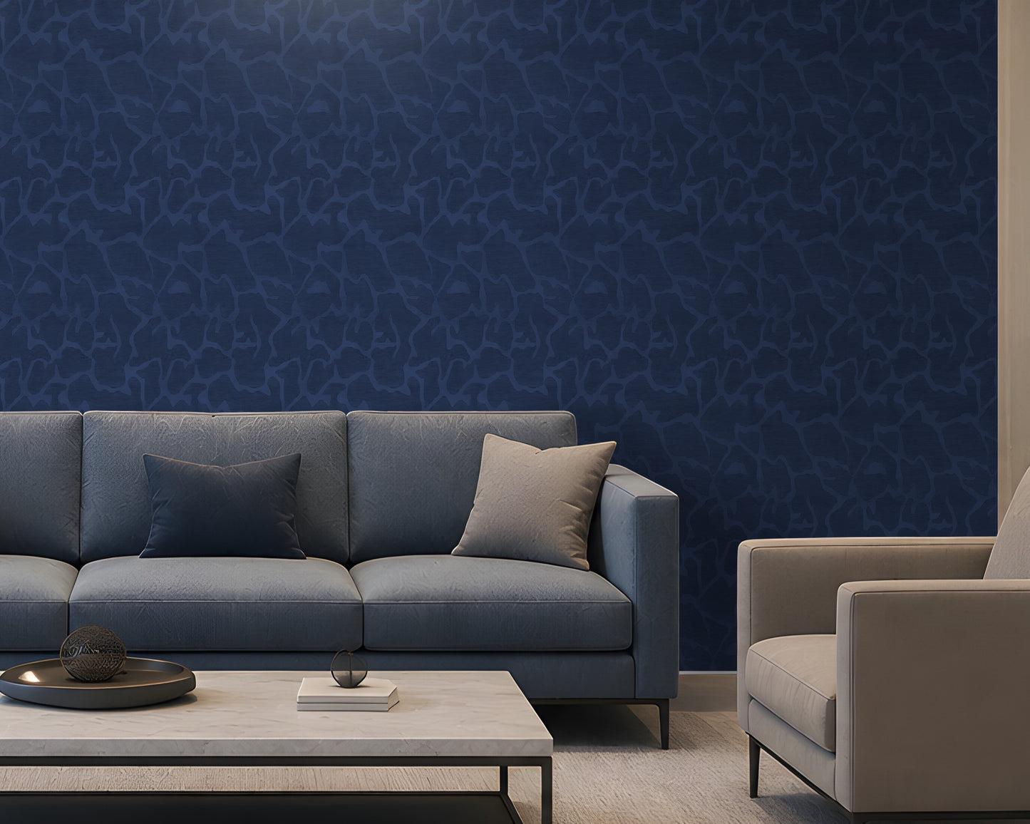 A modern living room setup featuring a prominent dark blue textured wallpaper on the back wall, a slate blue fabric sofa with two throw pillows, a light wood coffee table, and a light beige armchair.