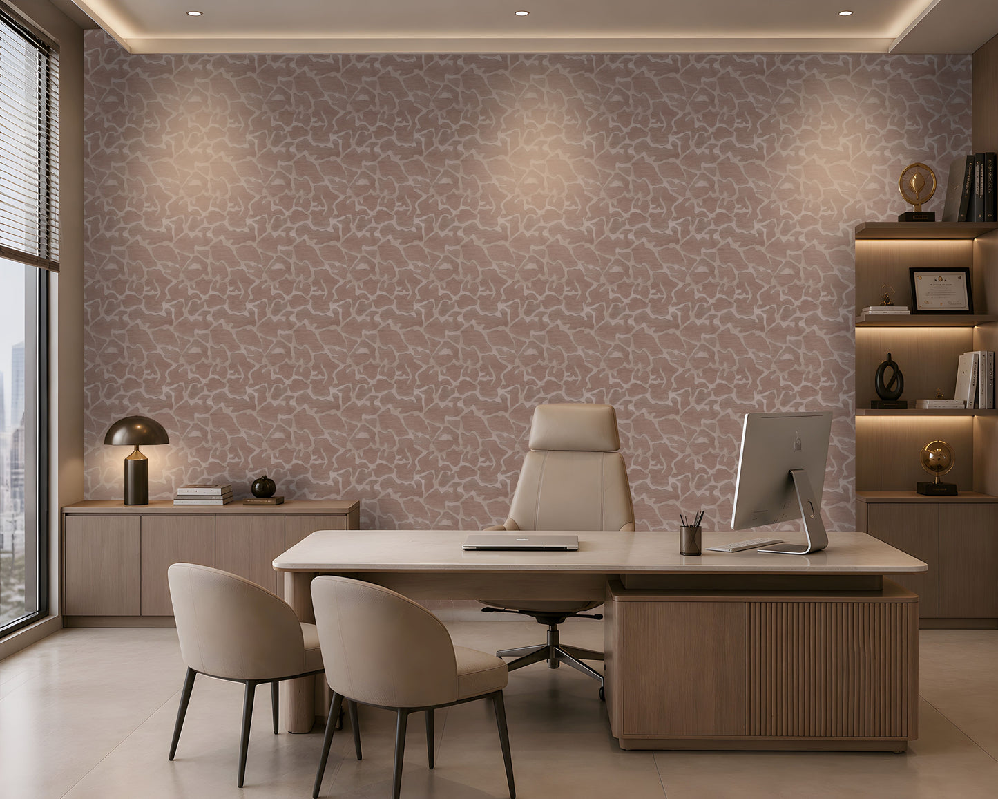 A modern office interior featuring a large desk, two beige chairs, a computer monitor, shelving, and a wall covered in a pink and beige abstract patterned wallpaper.