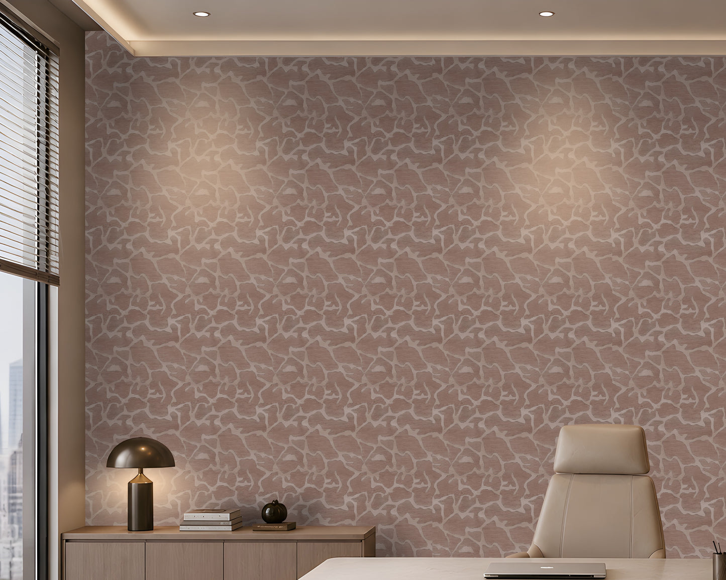 A modern office interior featuring a textured, abstract patterned wallpaper in dusty mauve and beige tones on the main wall. A light wood credenza with a black dome lamp and books sits on the left, and a beige leather office chair is on the right.