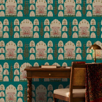 Shriji Darbar Heritage Wallpaper in Aqua blue featuring traditional Indian palace arches, royal darbar illustrations, ornamental motifs, and elegant cypress trees in a seamless repeating pattern, showcased in a refined study room with carved wooden furniture, brass lighting, bookshelves, and warm natural sunlight.