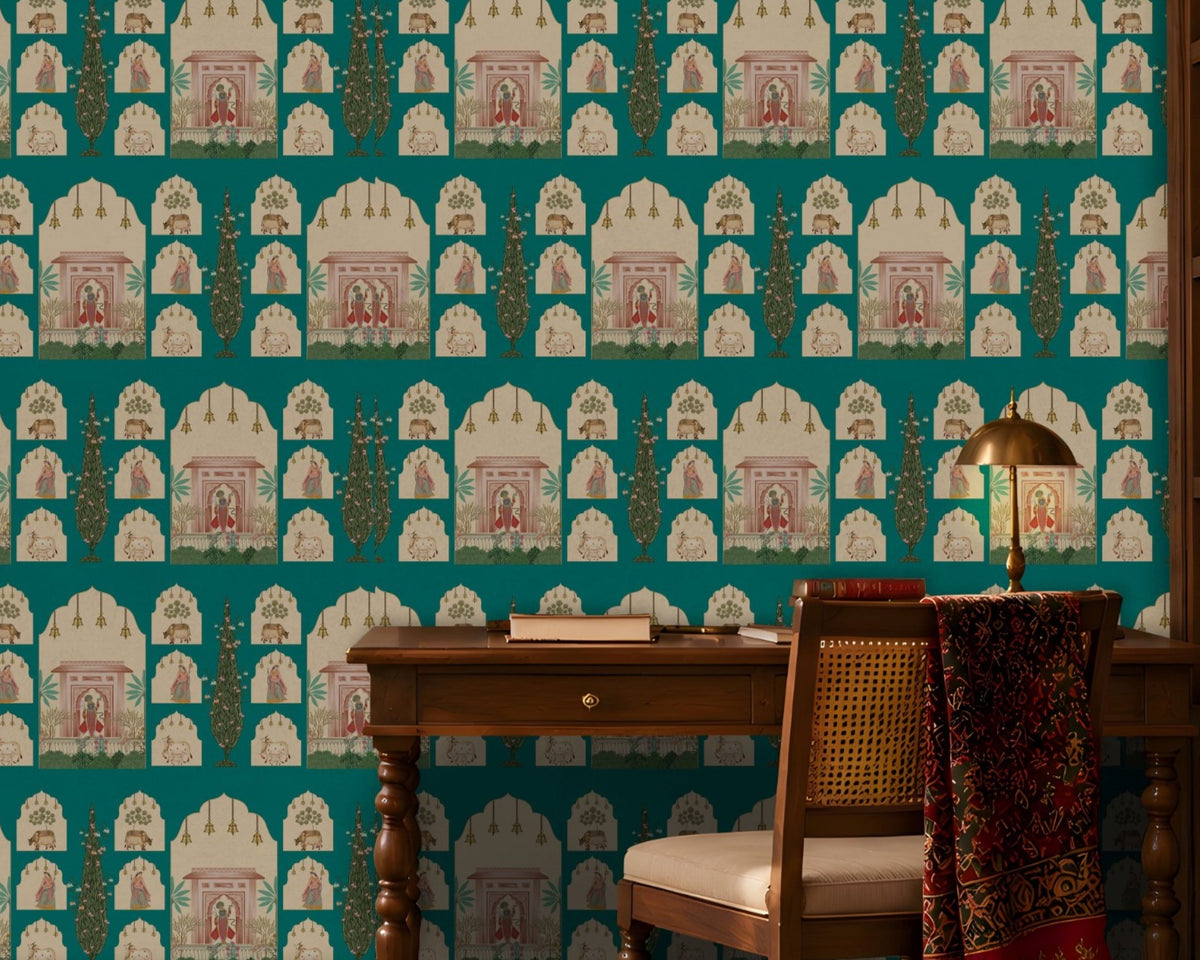 Shriji Darbar Heritage Wallpaper in Aqua blue featuring traditional Indian palace arches, royal darbar illustrations, ornamental motifs, and elegant cypress trees in a seamless repeating pattern, showcased in a refined study room with carved wooden furniture, brass lighting, bookshelves, and warm natural sunlight.