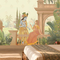 A large wall mural featuring a classical Indian scene with Lord Krishna and the Queen of Heaven, set in a lush tropical garden with peacocks and palm trees, shown in a styled bedroom setting.