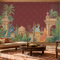 A large wall mural featuring a traditional Indian scene with Lord Krishna and Radha, peacocks, and architectural motifs, displayed in a beautifully decorated living room with a sofa, armchair, and wooden coffee table.