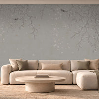 Modern luxury living room featuring Silent Breeze Mist Grey Botanical Birds Wallpaper with delicate branches, subtle floral motifs, a cream sectional sofa, minimalist coffee table, and warm ambient lighting.