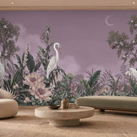 Whimsical mural featuring white herons amidst lush tropical flora dominates the back wall of a modern, neutral-toned living room. The mural displays a muted purple backdrop with a crescent moon, detailed green foliage, pale ivory blossoms, and tall trees.