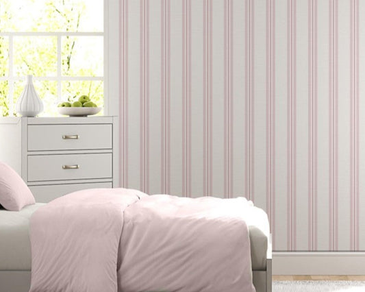 A bright bedroom features a soft pink and white vertically striped wallpaper.
The detailed design shows thin, evenly spaced pink stripes running down a white base.
In front, a neatly made bed with a light pink comforter rests near a matching nightstand.
The relaxing space is complete with two light grey dressers, large windows, and a rug.