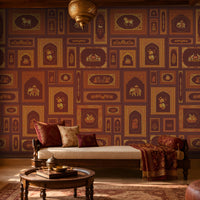 The Royal Rajputana Courtyard wallpaper in Imperial Burgundy featuring intricate Rajasthani palace-inspired motifs, elephant illustrations, floral artwork, Mughal arches, and antique gold detailing in a luxurious heritage-style living room.