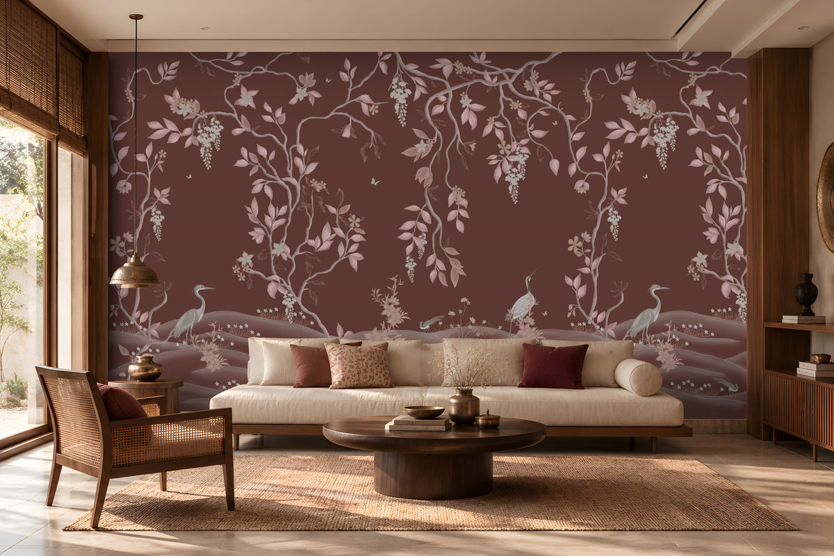 Timeless Avian Garden Mural in rich burgundy brown featuring delicate pink botanical branches, graceful birds, soft floral details, and flowing foliage. The elegant nature-inspired wallpaper creates a warm and sophisticated living room with neutral seating, dark wood furniture, natural textures, and soft ambient lighting.
