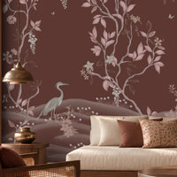 Timeless Avian Garden Mural in rich burgundy brown featuring delicate pink botanical branches, graceful birds, soft floral details, and flowing foliage. The elegant nature-inspired wallpaper creates a warm and sophisticated living room with neutral seating, dark wood furniture, natural textures, and soft ambient lighting.