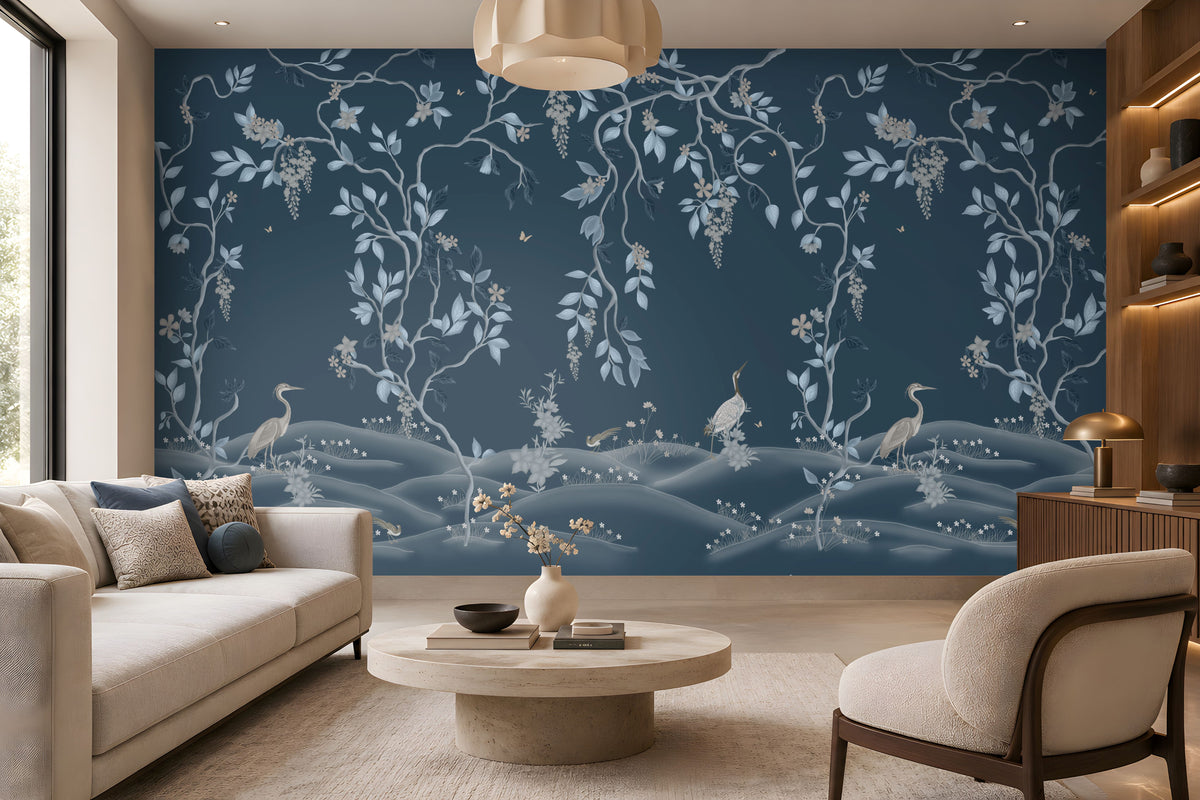 Timeless Avian Garden Mural in deep navy blue featuring delicate botanical branches, soft blue and ivory leaves, graceful birds, floral details, and flowing foliage. The elegant nature-inspired wallpaper creates a sophisticated modern living room with neutral curved furniture, warm wood accents, natural textures, and soft ambient lighting.
