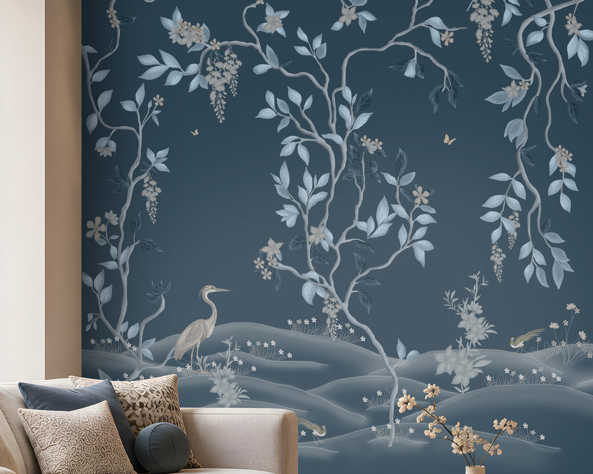Timeless Avian Garden Mural in deep navy blue featuring delicate botanical branches, soft blue and ivory leaves, graceful birds, floral details, and flowing foliage. The elegant nature-inspired wallpaper creates a sophisticated modern living room with neutral curved furniture, warm wood accents, natural textures, and soft ambient lighting.
