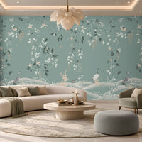 Timeless Avian Garden Mural in Misty Blue featuring delicate botanical branches, soft ivory flowers, graceful foliage, and elegant bird illustrations, creating a serene nature-inspired living room with a sophisticated misty blue and neutral colour palette, curved furniture, warm lighting, and contemporary décor.
