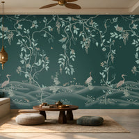 Luxurious living room featuring a teal botanical wallpaper mural with delicate vines, foliage, blossoms, and graceful birds, complemented by a neutral sofa, wooden coffee table, textured rug, warm pendant lighting, and elegant wooden cabinetry.
