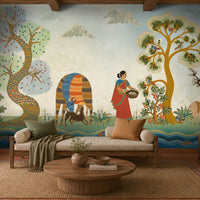 Traditional Gond Art wallpaper mural featuring hand-painted Indian folk art with colorful trees, birds, deer, cattle, and a village woman on a soft ivory background, showcased in a warm contemporary living room with natural wood furniture and earthy décor.