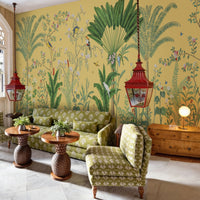 An architectural perspective of a sophisticated lounge featuring the Tropical Jungle Haven Mural in Mellow Yellow as a full-scale feature wall. The mural’s detailed wildlife narrative pairs elegantly with warm wood furniture and natural sunlight, creating a grand and cultured interior sanctuary.