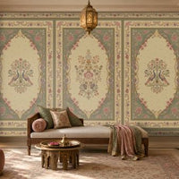 Vanamala Garden Mural Wallpaper - Antique Olive Green featuring elegant peacock motifs, floral bouquets, and ornate heritage-inspired frames in soft dusky teal blue and ivory tones, showcased in a luxurious Indian living room with carved wooden furniture, warm lighting, and classic decorative accents.