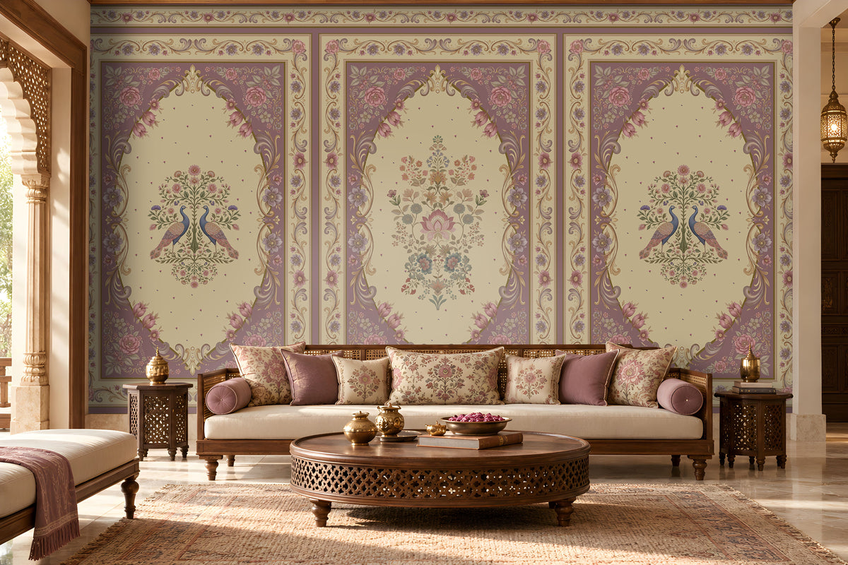 Vanamala Garden Mural Wallpaper - Muted Plum featuring graceful peacock motifs, delicate floral bouquets, and ornate heritage-inspired borders in soft dusky teal blue and ivory tones, showcased in an elegant Indian living room with carved wooden furniture and traditional décor.