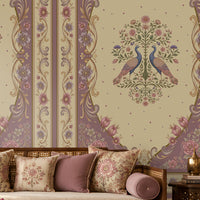 Vanamala Garden Mural Wallpaper - Muted Plum featuring graceful peacock motifs, delicate floral bouquets, and ornate heritage-inspired borders in soft dusky teal blue and ivory tones, showcased in an elegant Indian living room with carved wooden furniture and traditional décor.