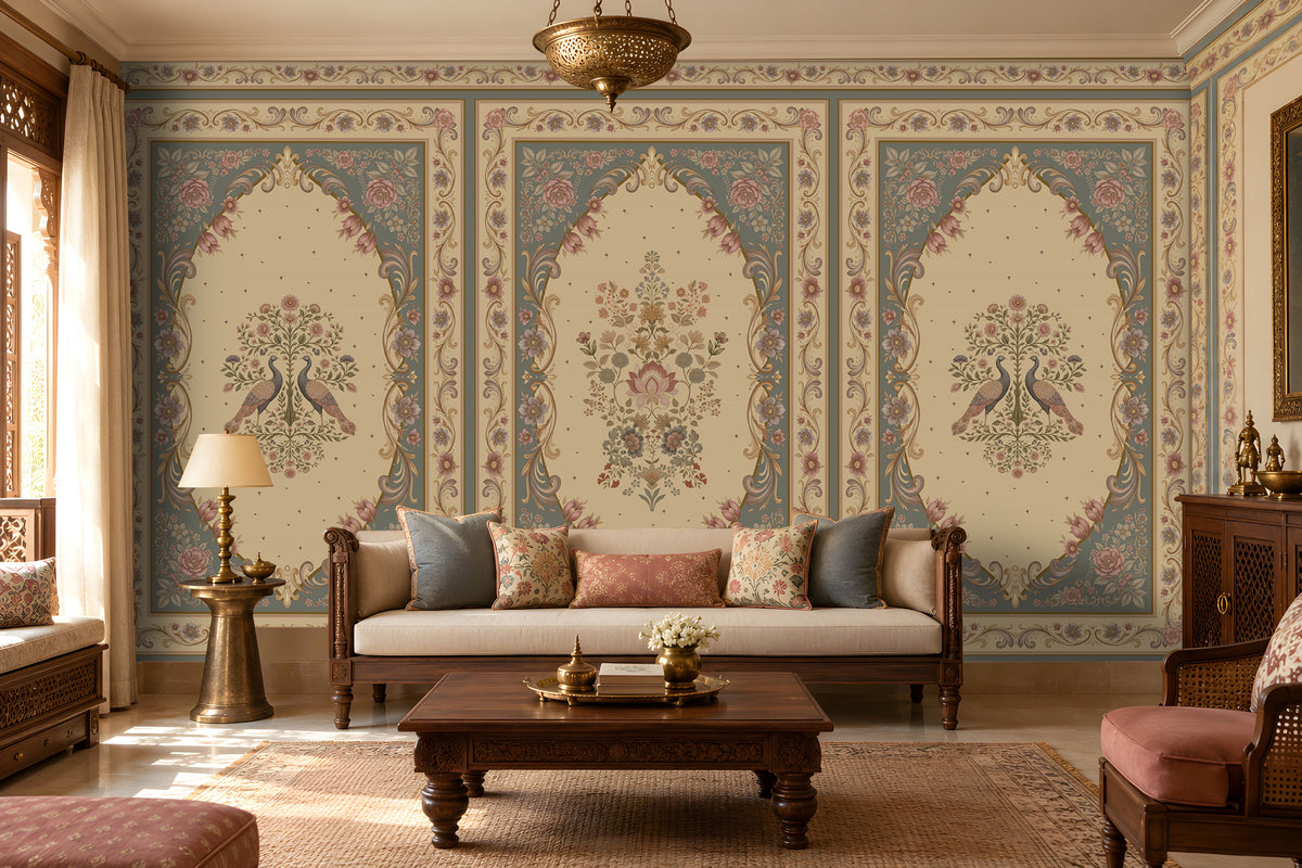 Vanamala Garden Mural Wallpaper - Slate Blue showcasing ornate peacock motifs, intricate floral medallions, and decorative heritage borders in dusky teal blue and ivory tones, styled in a luxurious traditional living room with carved wooden furniture, soft furnishings, and warm natural lighting.